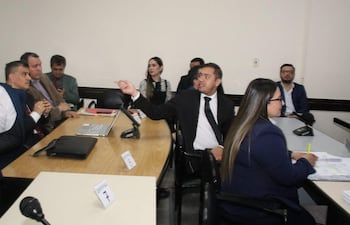 Miguel Prieto gesticula en sala, acompañado de defensores en trajes oscuros y visibles expresiones de preocupación.
