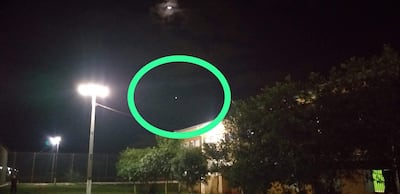 La imagen muestra un entorno nocturno, probablemente al aire libre. No hay personas visibles en la escena. Se aprecian varias fuentes de luz, incluyendo dos faroles que iluminan la área cercana y sugieren que es un espacio utilizado para actividades, posiblemente un campo deportivo.
En la parte superior, hay una luna parcialmente oculta por nubes, y en el área marcada, se puede ver un objeto luminoso, que podría ser un planeta o una estrella brillante, pero no se puede identificar con certeza su naturaleza.
No se reconocen elementos visuales relacionados con un equipo de fútbol, como camisetas o escudos, y no hay monumentos o lugares icónicos identificables en la imagen. La ambientación parece ser serena y tranquila, sin acciones específicas en curso. No hay texto visible ni elementos adicionales de contexto noticioso.