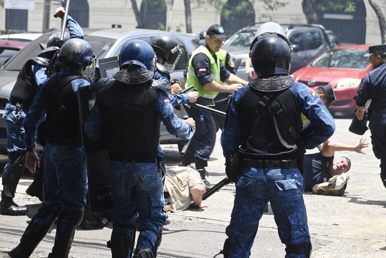 Cascos azules y agentes policiales golpean a un manifestante contra ley que crea la Superintendencia de Jubilaciones.