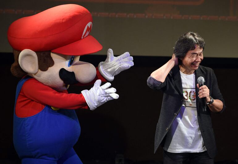 Esta foto de archivo tomada el 13 de septiembre de 2015 muestra al creador de juegos de Nintendo, Shigeru Miyamoto (D), reaccionando mientras está junto al personaje "Super Mario" (I) durante una presentación en vivo de la música más conocida de Mario para conmemorar el 30 aniversario del juego en Tokio.