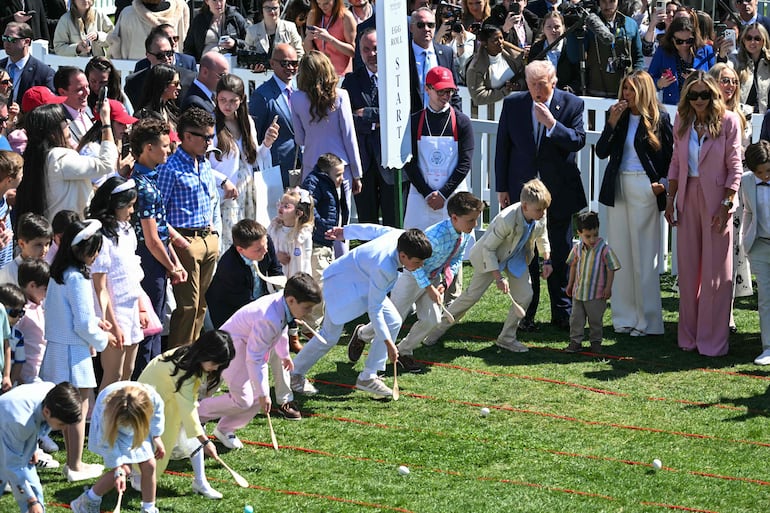 Donald Trump y Melania Trump hacen sonar silbatos mientras los niños participan en la tradicional búsqueda de huevos de Pascua en el jardín sur de la Casa Blanca. (SAUL LOEB / AFP)