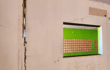 Interior del Centro de Salud de Itakyry con pared agrietada, ventana al exterior y piso desgastado.