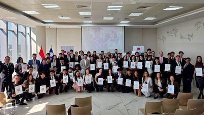 Grupo de jóvenes con sonrisas en vestimenta formal, rodeados de banderas de Paraguay y Taiwán en un salón elegante.