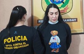 Dos mujeres en oficina del Departamento Contra el Crimen Organizado, una lleva camiseta policial y otra un suéter negro con un diseño de oso.
