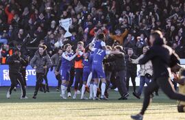 Los aficionados del Macclesfield invaden el campo para celebrar la victoria del equipo con los jugadores (centro) al finalizar el partido de fútbol de la tercera ronda de la FA Cup inglesa entre el Macclesfield Town y el Crystal Palace, en el estadio Leasing.com Stadium, Moss Rose, en Macclesfield, al norte de Inglaterra