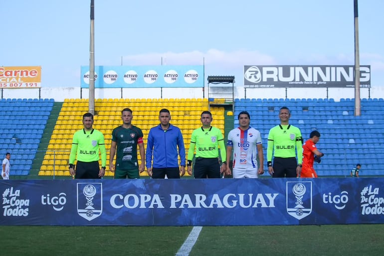 Los capitanes de ambos equipos, Rodrigo Vera (izquierda) y Fidencio Oviedo, posan con la terna arbitral.