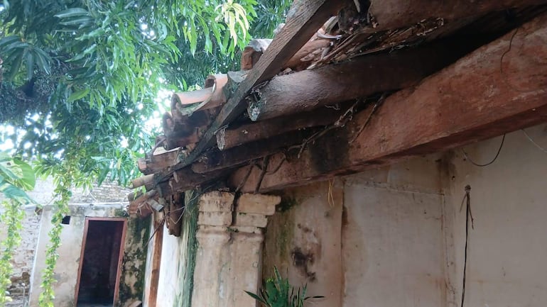 Ambiente exterior de la Casa de la Cultura en mal estado, con techado deteriorado y vegetación frondosa alrededor.