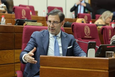 Silvio Ovelar, con traje oscuro y corbata celeste, habla en el Senado, mientras otros senadores lo observan.