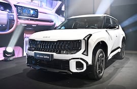 SUV All-new Seltos blanco exhibido en evento con pantalla mostrando detalles de su interior y ambientación dramática.