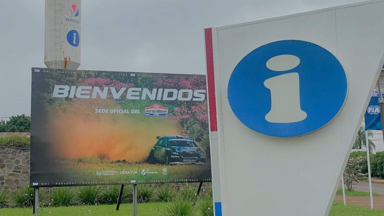 Cartel de bienvenida para el Rally del Paraguay con un coche de rally en un entorno natural. Flora cuidada y ambiente exterior.