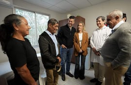 Grupo de seis personas sonríen en un ambiente acogedor; Santiago Peña destaca en abrigo oscuro, conversando amigablemente con otros.
