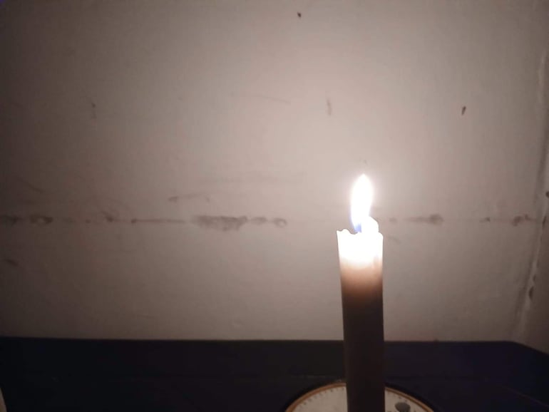 Vela marrón encendida sobre un mueble en un ambiente oscuro, sugiriendo calma y reflexión.