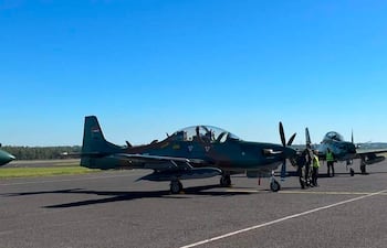Tres aviones caza Super Tucano alineados en la pista con cielo despejado y soleado. No se observan personas en la imagen.