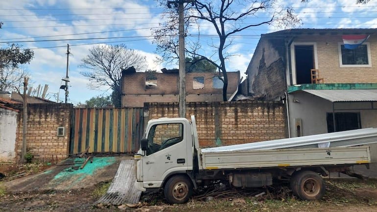 Camión blanco estacionado entre escombros de una edificación dañada, con cielo nublado de fondo.