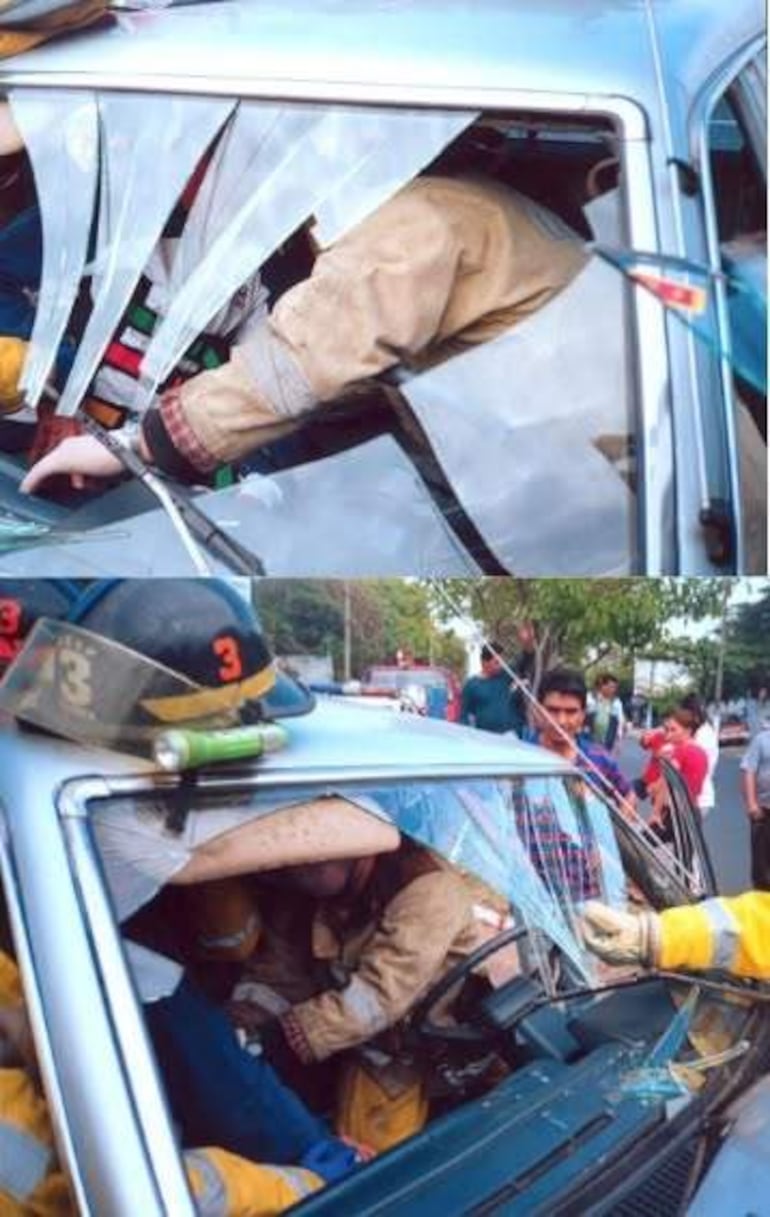 Bomberos en uniforme negro ayudando a una persona en un auto con vidrio roto, rodeados de espectadores interesados.