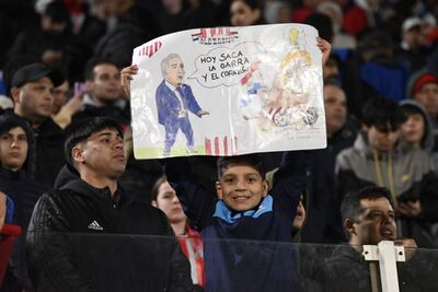 El pequeño hincha paraguayo y un cartel dedicado a Gustavo Alfaro en la previa del partido de la selección de Paraguay contra Ecuador por la fecha 17 de las Eliminatorias Sudamericanas 2026 en el estadio Defensores del Chaco, en Asunción, Paraguay.