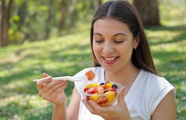 Mujer come una ensalada de frutas.