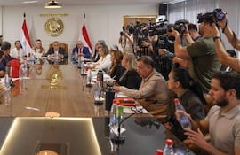 Reunión formal con varios adultos sentados, la ministra Barán entre ellos, en un ambiente bien iluminado con documentos sobre la mesa.