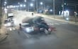 Accidente nocturno en carretera, camión colisiona con automóvil, nube de polvo y escombros en el impacto.