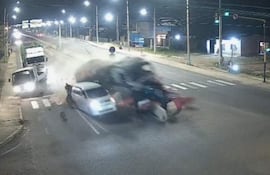 Accidente nocturno en carretera, camión colisiona con automóvil, nube de polvo y escombros en el impacto.