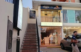 Un hombre con camiseta oscura camina frente a la joyería Vio Gold en un entorno urbano y comercial.
