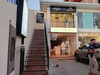 Un hombre con camiseta oscura camina frente a la joyería Vio Gold en un entorno urbano y comercial.