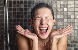 Una mujer se baña bajo un chorro de agua fría.