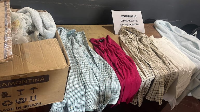 Mesa en comisaría con varias prendas y caja de cartón, mostradas como evidencia de un robo en Limpio.