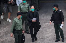 El activista prodemocracia, Benny Tai (C) camina custodiado por las fuerzas dirigidas ahora por el régimen de Pekín.