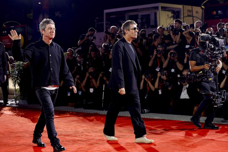 Noel y Liam Gallagher caminando en la alfombra roja del festival de Venecia, ante decenas de fotógrafos. EFE/EPA/FABIO FRUSTACI
