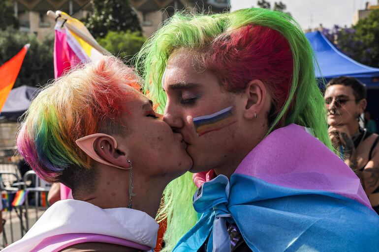 Dos participantes de la marcha del orgullo gay se besan durante la actividad. 