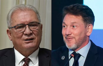 Emiliano Rolón, con saco negro y gafas, dialoga con Alejandro Domínguez, ambos en traje formal, en ambiente de conferencia.