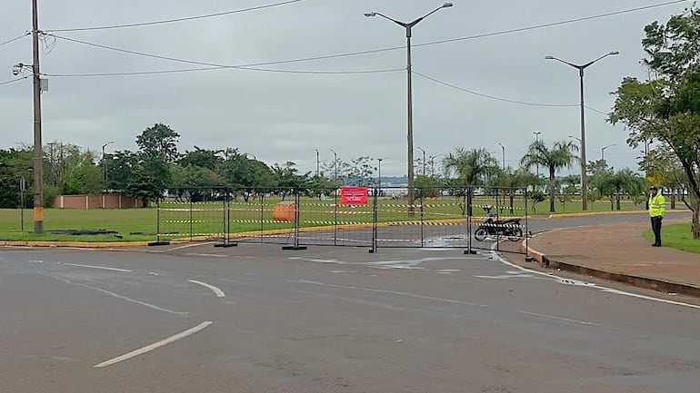 Policía con chaleco amarillo controla el acceso previo al Mundial de Rally, con lugar verde y pavimento húmedo al fondo.