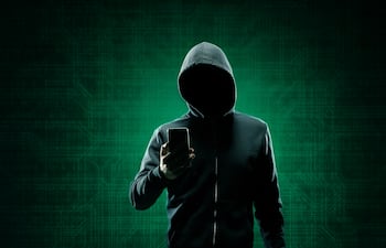 Un hombre con capucha y un teléfono celular en la mano.