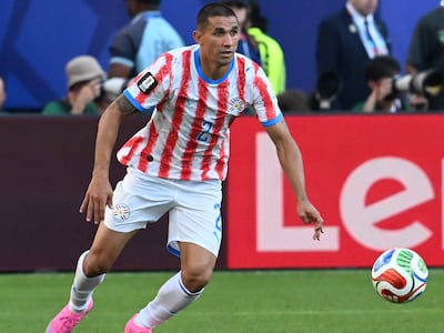 Víctor Gustavo Velázquez Kururu corre con el balón, vistiendo camiseta rojiblanca con el número 2, mientras se observa un estadio lleno al fondo.