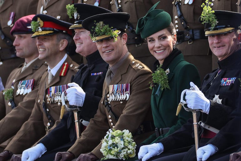 Kate Middleton sentada con miembros actuales y antiguos de la Guardia Irlandesa durante una visita al cuartel de Mons, en Aldershot, para conmemorar el Día de San Patricio. (Adrian DENNIS / AFP)