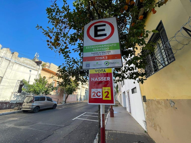 Señal de estacionamiento tarifado en calle de Asunción, con pintadas apoyando a Nasser concejal, vehículo estacionado en el lado.