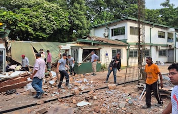 Empleados de la empresa atacada observan los destrozos causados por los criminales.