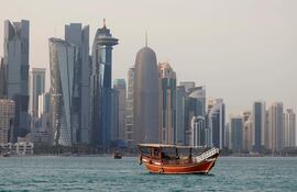 Un dhow tradicional transporta turistas frente al horizonte de Doha el 5 de julio de 2025.