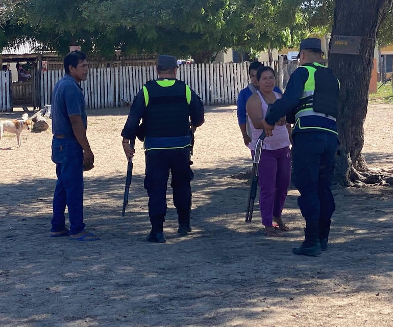 Dos policías con uniforme oscuro conversan con pobladora en comunidad indigena