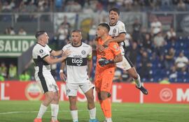 Los jugadores de Olimpia celebran con el arquero Lucas Verza (naranja) después del penal atajado en el partido frente a Peñarol por la tercera fecha del Grupo H de la Copa Libertadores 2025 en el estadio Defensores del Chaco, en Asunción, Paraguay.