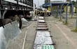 Tres agentes de seguridad en uniforme de camuflaje junto a un camión con cajas abiertas en un punto de control.