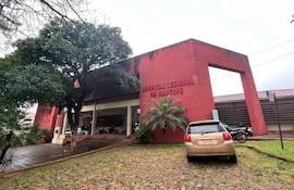 Hospital Regional de Caacupé, edificio rojo y moderno con vehículos estacionados y árboles alrededor, en un día nublado.