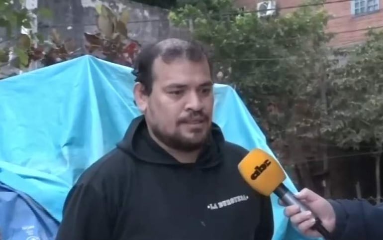 Hombre de mediana edad con barba en sudadera oscura 'La Buti', siendo entrevistado por un periodista con micrófono de ABC Color.