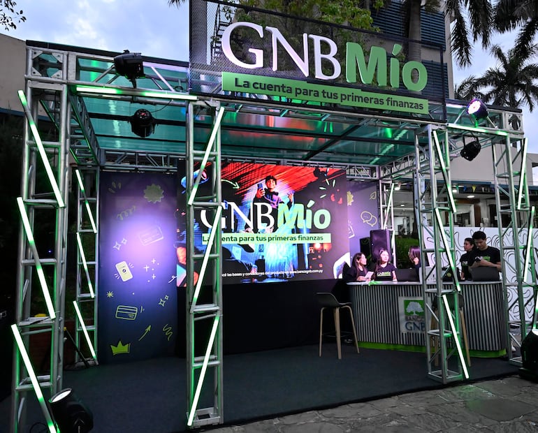 Montaje del evento GNB Mío con logo en pantalla grande y estaciones de trabajo iluminadas en verde.