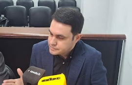 Hernán Rivas, con camisa negra y blazer azul, habla mientras su abogada Alba Záracho lo escucha, rodeados de micrófonos.