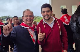 Camilo Pérez sonriente en traje oscuro, levantando un dedo índice, símbolo de la Lista 1, junto al presidente de la Juventud Colorada, rodeados de otros correligionarios en el día de proclamación de las candidaturas de la ANR.