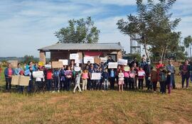 La imagen corresponde a una manifestación realizada por los padres de familia, acompañados de los niños frente, a la pequeña construcción de la escuela  en San Cayetano.