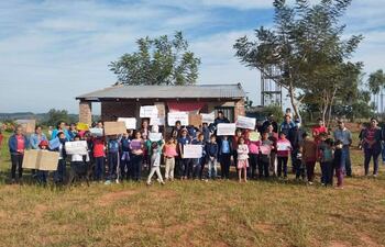 La imagen corresponde a una manifestación realizada por los padres de familia, acompañados de los niños frente, a la pequeña construcción de la escuela en San Cayetano.