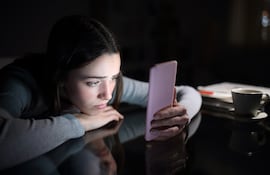 Una joven deprimida mira su teléfono celular.